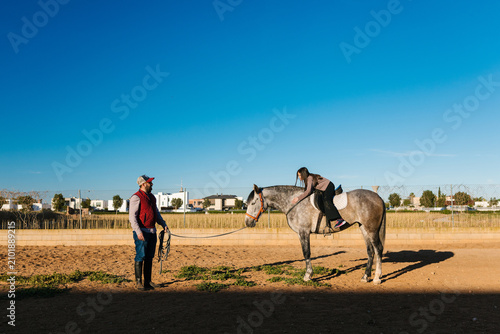 Equestrian instructor teaching girl riding dapple gray horse
