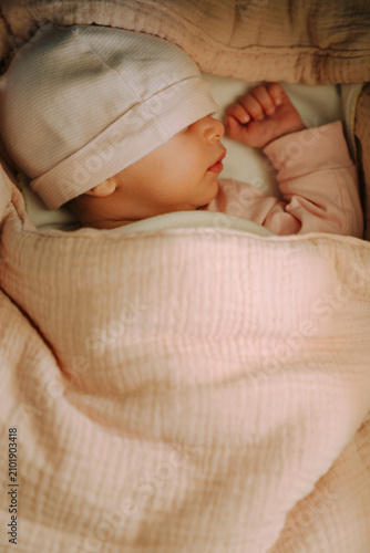 Sleeping newborn baby wrapped in a pink muslin blanket