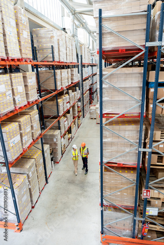 Logistics workers walking through large warehouse aisle