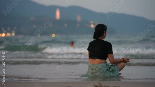 Woman meditating on beach shoreline with sea waves and Lady Buddha in Da Nang, Female practicing mindfulness by ocean at sunset with coastal mountains 4k