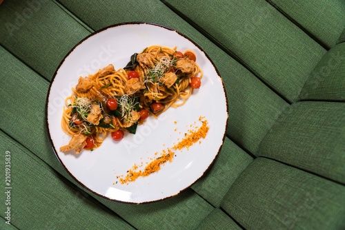 Obraz na płótnie Pasta Delight: A delectable plate of spaghetti pasta, adorned with succulent meat, vibrant cherry tomatoes, fresh greens, and a sprinkle of cheese