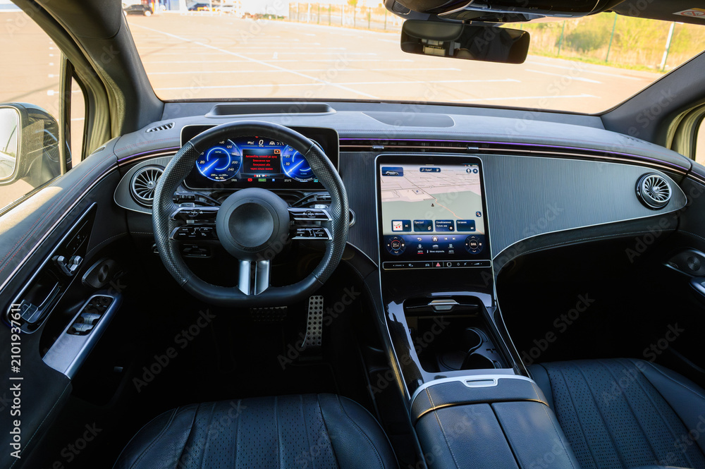 Obraz premium Dashboard and cockpit interior layout of a modern luxury car featuring a digital instrument cluster, steering wheel, and a large multimedia navigation touchscreen display.