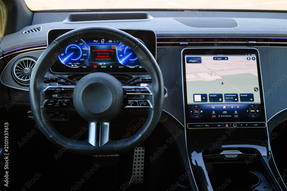 Obraz premium Driver cockpit and dashboard of a modern luxury car with a perforated leather steering wheel, digital instrument cluster, and a large multimedia navigation display, close up.