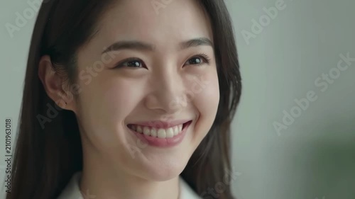 Close-up of happy young Asian woman smiling with natural background