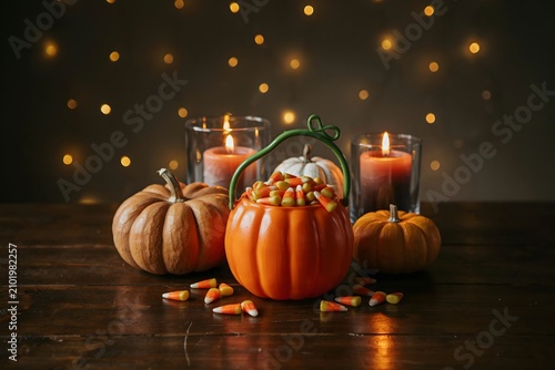 Festive halloween still life with pumpkins candy corn and glowing candles on a rustic wood table