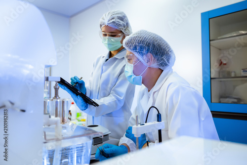 Bild auf Leinwand Asian scientists team checking pharmaceutical research data on digital tablet in