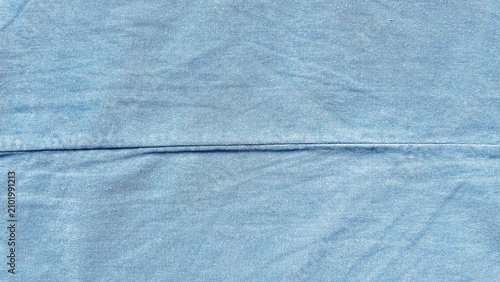 light blue denim fabric texture with horizontal seam showing natural weave pattern and soft washed cotton material background