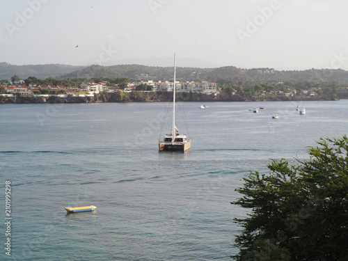 Sailboat in ocean water near a coastal area with houses.