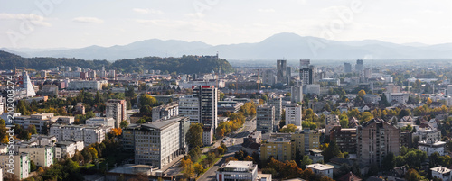 Aerial view shows Ljubljana, Slovenia with its urban skyline, historic buildings, and old castle on a clear day.