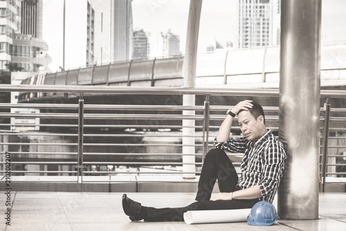 Fotografija Asian engineer man who sitting on the floor in feeling sad because his business failed and unemployed