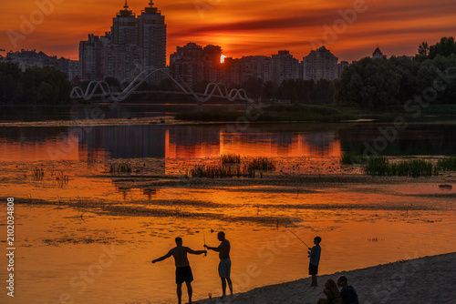 Foto Beautiful golden sunset over Dnieper river in Kyiv with silhouettes of fishermen