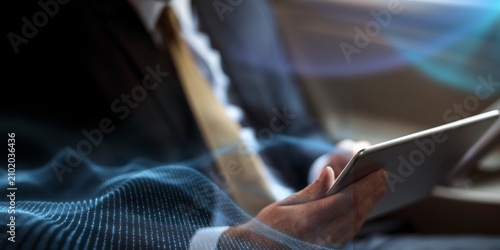 Tableau sur toile Person in a suit using a tablet, with digital wave overlay.