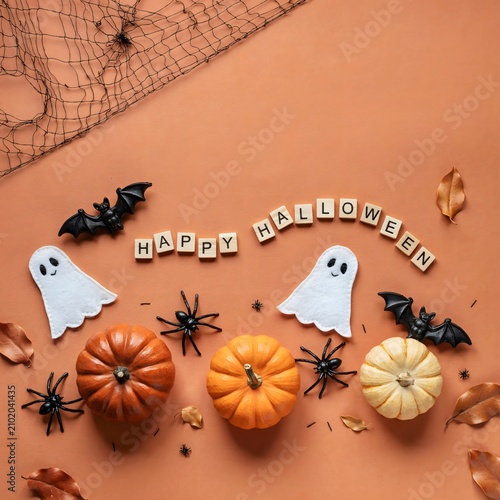 Festive halloween still life with pumpkins ghosts bats and letter blocks on a terracotta background