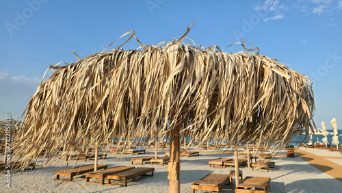 Obraz na płótnie Thatch beach umbrella and sun loungers on a sandy beach