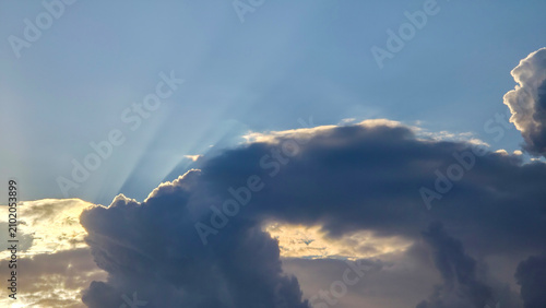 Foto Sun rays breaking through thick dark storm clouds in sky