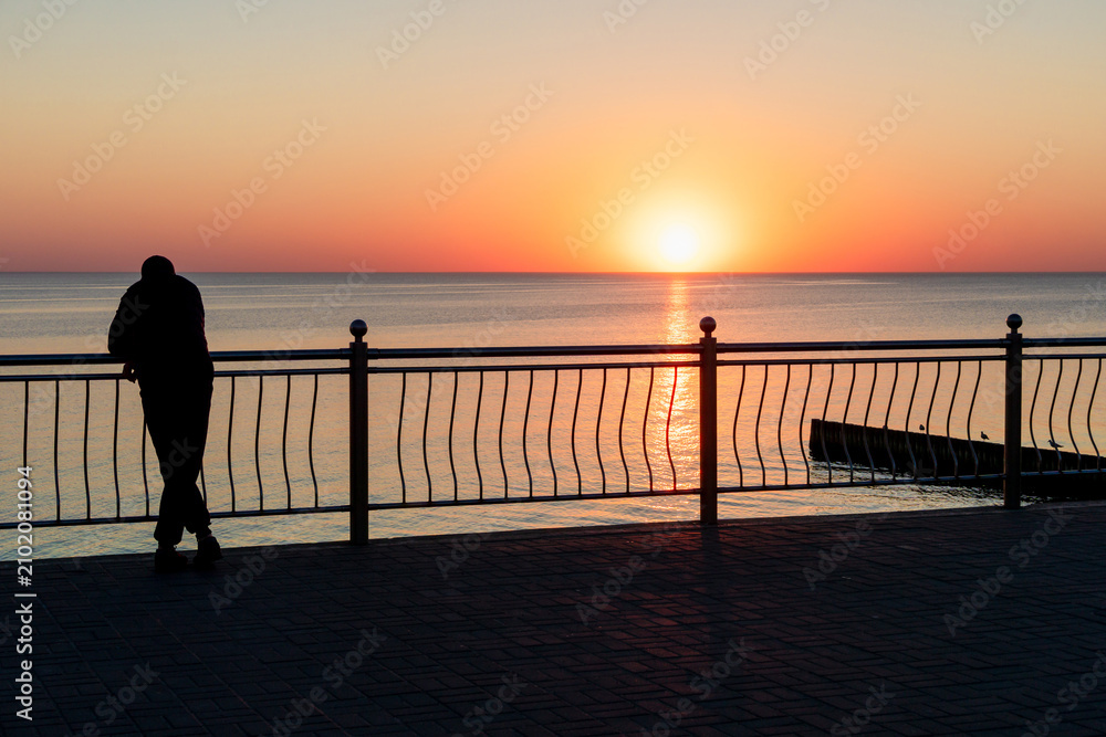 Fototapeta premium Man Watching Sunset from Seaside Promenade