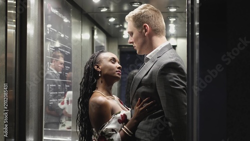 Foto A handsome young man and a beautiful woman look at each other and smile while standing in an elevator