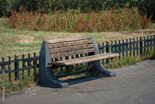 An old and worn bench in the city park. wood and metal construction. wooden and concrete material.