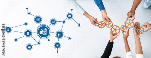 Fotografie Hands joining together to manipulate gears, showcasing collaboration in performance analysis and business strategy development within a modern office environment
