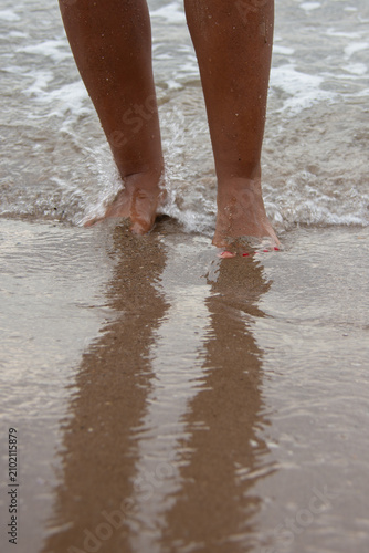 Close up of woman's feet in gentle ocean waves on beach