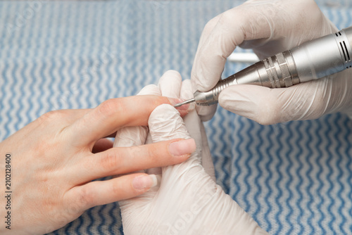 Professional Nail Technician Using Electric Nail Drill During Hardware Manicure Procedure