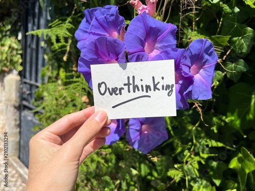 Overthinking - hand with text and purple flowers in background, mental health concept