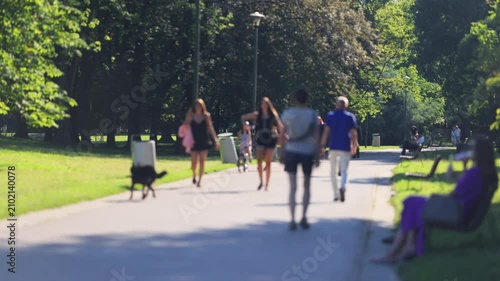 Unrecognizable people walking on the streets of Warsaw. People walking in the park. Sunny, hot, summer weather.