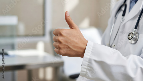 Doctor giving thumbs up while standing in a medical office  
