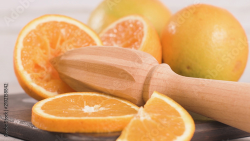 Fotografía Wooden Juicer Reamer with Fresh Slices and Halves of Orange
