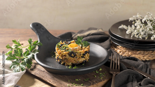 Traditional Portuguese Bacalhau a Bras Plated with Black Olives and Egg Yolk in a Black Skillet