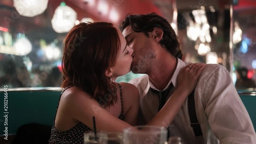 Young couple sharing an intimate kiss in a dimly lit retro diner booth