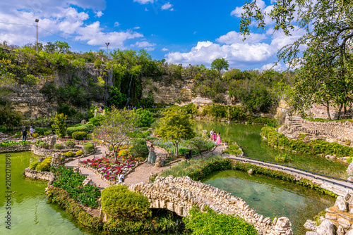 Elevated wide view of the beautiful sunken Japanese Tea Garden featuring stone bridges, winding paths, ponds, and visitors in San Antonio.