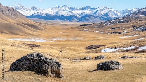 Vast, sun-drenched plains stretch towards snowy mountains.