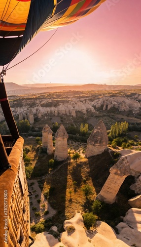 Hot air balloon flying over fairy chimneys in Cappadocia valley at sunrise
