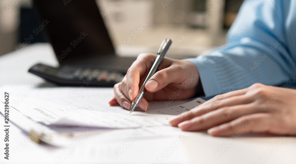 Fototapeta premium Close up of businesswoman hand writing on tax form at office desk. Accountant auditing financial invoice receipt, calculating budget or corporate management concept.
