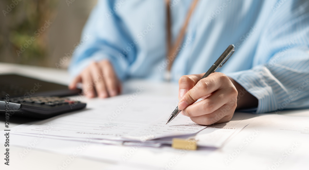 Fototapeta premium Businesswoman reviewing financial documents, tax paperwork, file folders, and business records on a laptop, representing accounting, document management, compliance, and office administration.