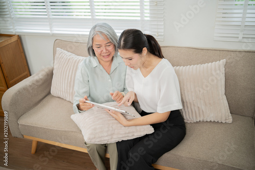 Quadro su tela An Asian caregiver gently holds an elderly woman's hand, providing attentive and