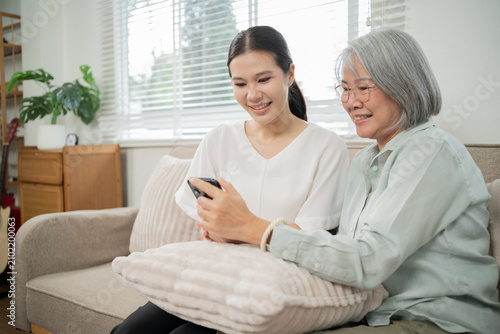 Schilderij op canvas An Asian caregiver gently holds an elderly woman's hand, providing attentive and