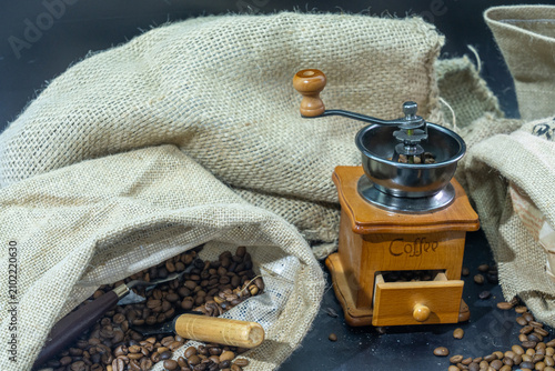 Still life of vintage hand coffee grinder with roasted beans and burlap sack
