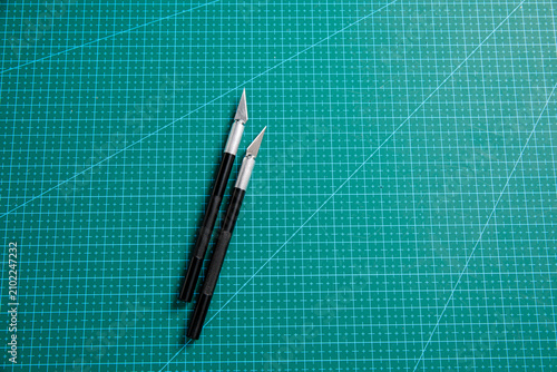 Two precision craft knives on green self-healing cutting mat for model making and graphic design