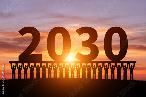 In the morning sun, numerous silhouettes of children are holding up the year 2030
