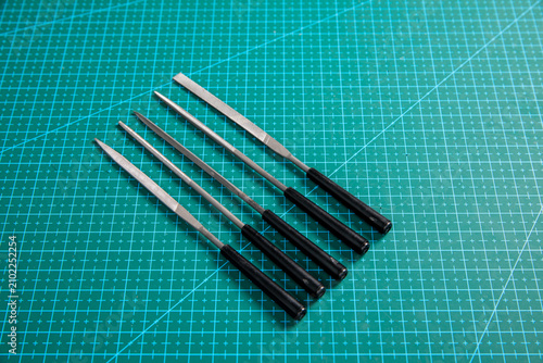 Obraz na płótnie Four precision metal files with black handles arranged diagonally on green cutti