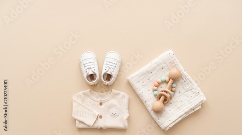 Cute organic newborn clothing, shoes, and wooden rattle concept for first-time parents, advertising campaigns