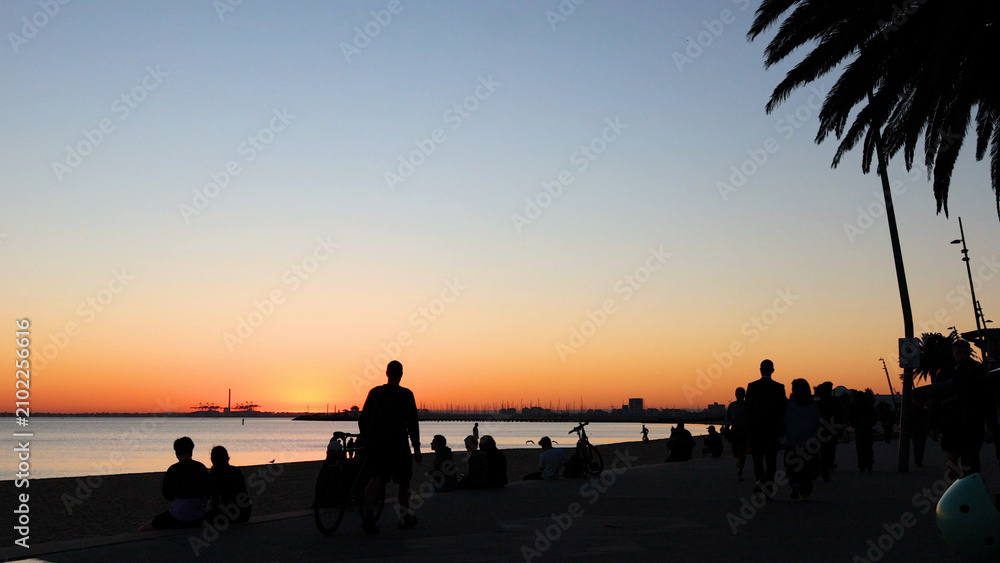 Obraz premium Silhouetted People Gathering on Brighton Beach During a Golden Sunset