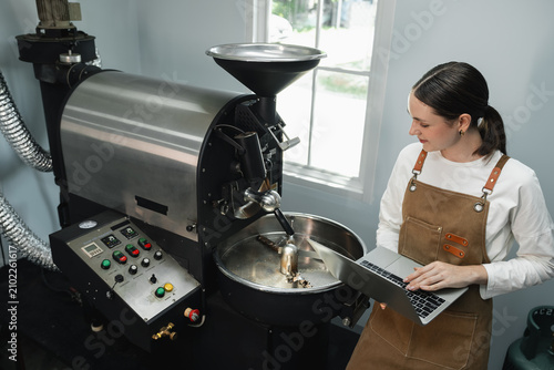 Foto Female Coffee Roaster Managing Specialty Coffee Production on a Laptop Beside a