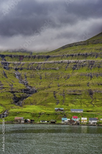 Little village on the foot of a the cliffs in Estuyroy, Faroe islands, Denmark