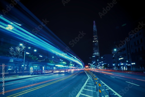 Принти на полотні SEOUL, SOUTH KOREA - JUN 23, 2019: A futuristic blue-toned street view showing long light trails of city buses heading toward the distant Lotte World Tower under a night sky