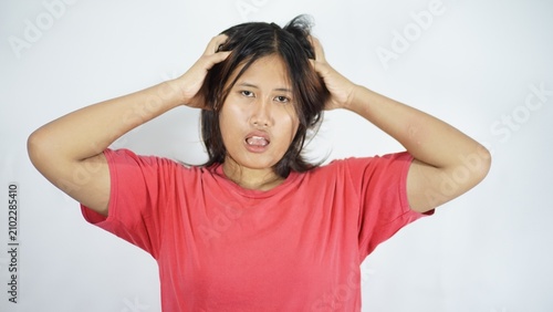 Obraz na płótnie Young woman frustrated, hands in hair, looking stressed and confused, white back