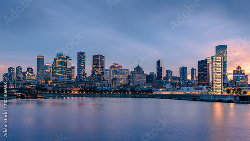 Montreal skyline at sunset seen from the Old Port, with downtown skyscrapers and the Port of Montreal Tower reflected in the Saint Lawrence River, Quebec, Canada