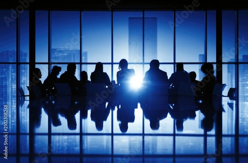 Silhouetted figures gather around a conference table, bathed in bright window light